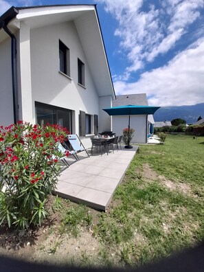 Una casa moderna con un patio, una mesa de comedor y sillas.