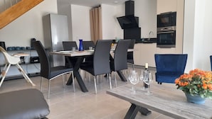 Een moderne eetruimte met een houten tafel, zwarte stoelen en een blauwe bank.