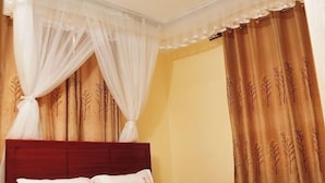 Quarto com cama, dossel branco e cortinas.