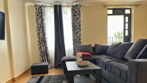 A living room with a grey sofa, a small coffee table, and a patterned rug. - Double N Suites Kakamega (Kakamega)