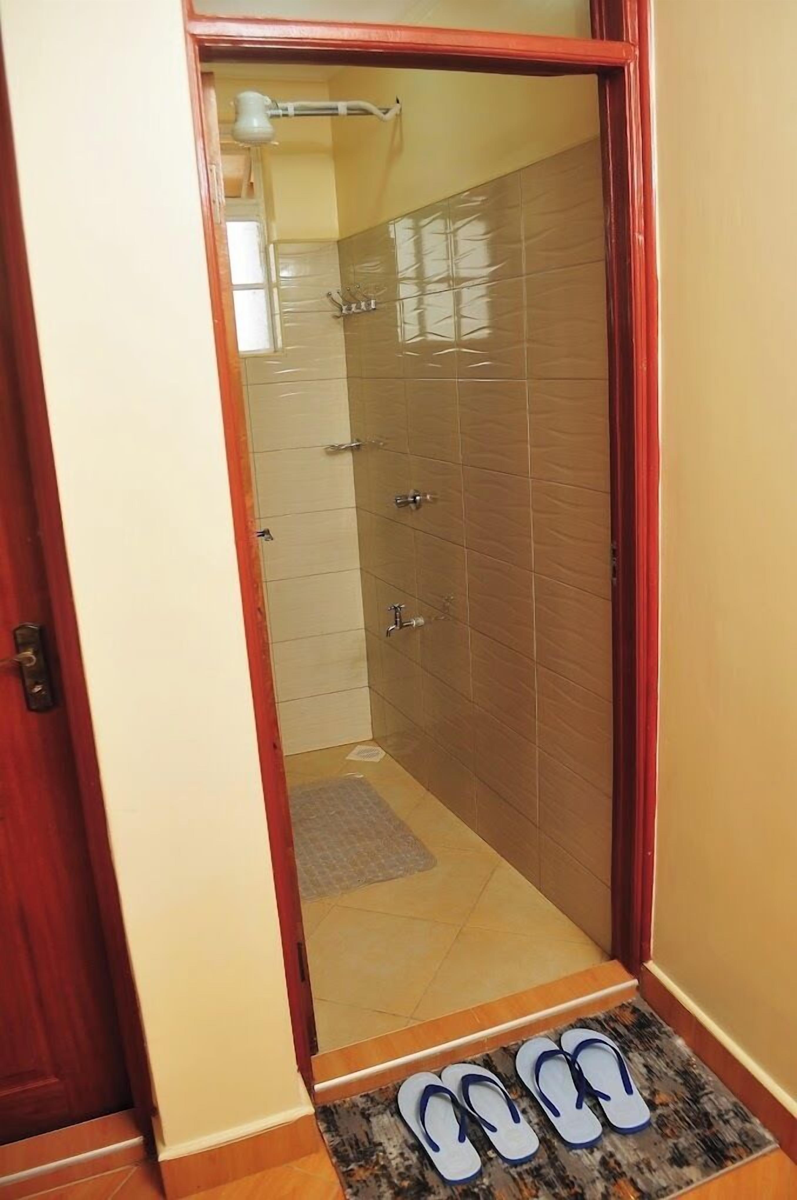 A bathroom with a shower, a towel rack, and a door with a red frame.