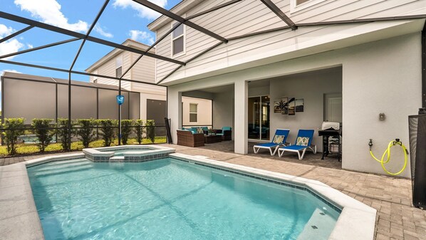A swimming pool with lounge chairs and a barbecue area, surrounded by a covered patio. - Luxe 7BR Solterra Villa Games Pool Themed Rooms (Davenport)