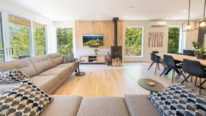 Een moderne woonkamer met een bank, een salontafel en een eethoek met stoelen.