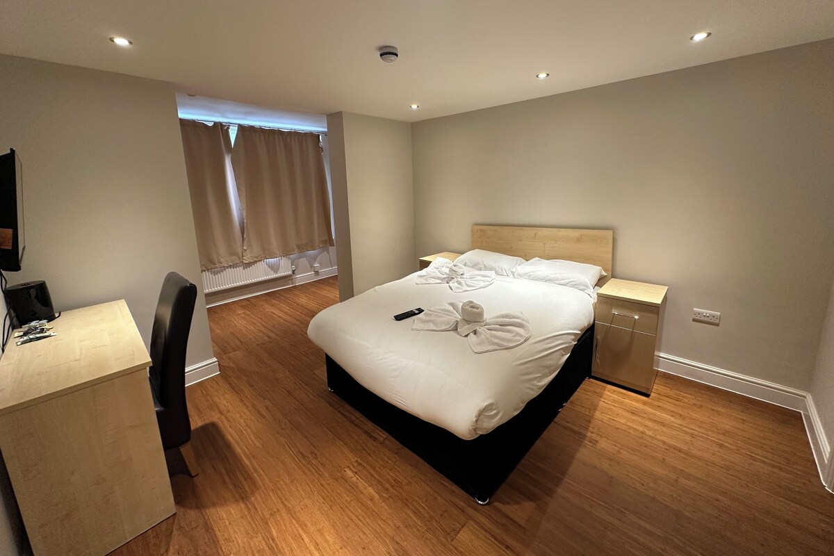 Ein Hotelzimmer mit einem Bett, Nachttischen, einem Schreibtisch und einem Sessel.