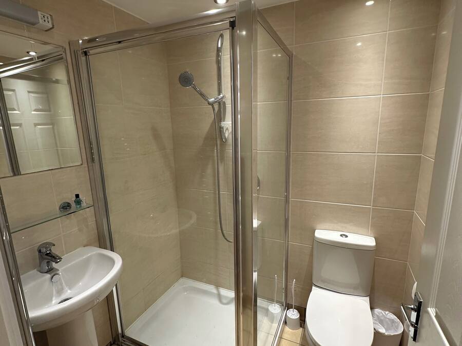 A modern bathroom with a glass-enclosed shower, a pedestal sink, and a toilet.