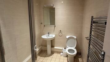 Ein modernes Badezimmer mit Duschkabine, Standwaschbecken, Toilette und Handtuchhalter.