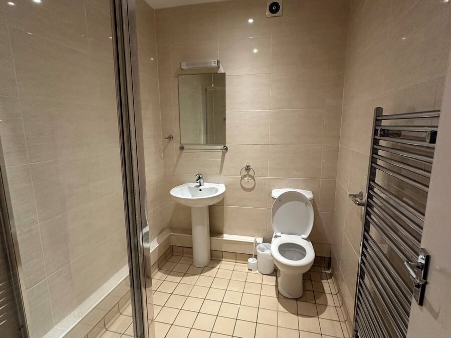 Ein modernes Badezimmer mit Duschkabine, Standwaschbecken, Toilette und Handtuchhalter.