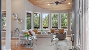 Tilava olohuone, jossa on korkea katto, suuret ikkunat ja moderni takka.