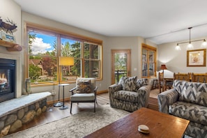 A spacious living room with a fireplace, large windows, and a dining area.