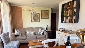 Una sala de estar acogedora con un sofá, sillas, una mesita de centro y una estantería.