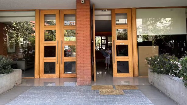 Entrada de un edificio con puertas de madera dobles y un pilar de ladrillo.