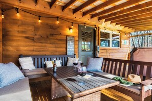 A wooden cabin interior with a wooden bench, a table with wine glasses, and a door with a sign. - 8 Miles to Pigeon Forge, 15 Miles to Gatlinburg, Sleeps 8, Pool Table, Hot Tub, Game Room (Sevierville)