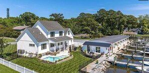 Une grande maison avec une piscine, un quai et des bateaux amarrés.
