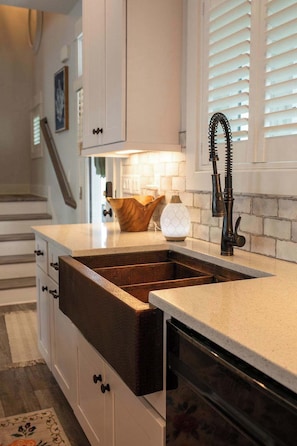 A kitchen with a built-in sink, white cabinetry, and a wooden countertop.