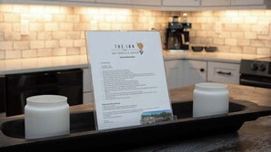Une cuisine avec des meubles blancs, un plan de travail noir et un présentoir affichant des informations sur l’hôtel.