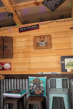A wooden interior with a wooden ceiling, a wall clock, a Tiki Bar sign, and a framed picture of a horse.