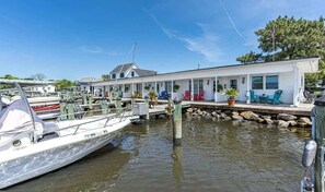 A marina with boats docked, a white building with a porch, and a flagpole.