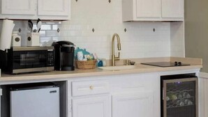 Une cuisine avec des meubles blancs, un four à micro-ondes, une machine à café et un lave-vaisselle.