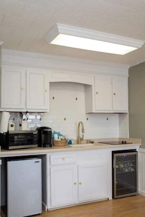 A kitchen with white cabinets, a microwave, a coffee maker, and a dishwasher.