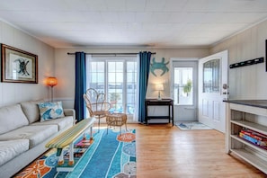 A living room with a sofa, a bench, a patterned rug, a table, and a chair.