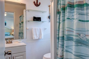 A bathroom with a white sink, a mirror, a towel rack, and a shower curtain with a wave pattern.