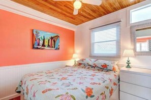 A bedroom with a wooden ceiling, a bed with a floral bedspread, a painting on the wall, and a window with blinds. - Inn on Turville Cottage, Sleeps 4, Waterfront (Berlin)