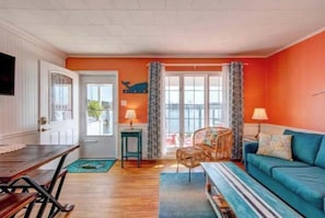 A room with a wooden dining table, a blue sofa, and a wicker chair.