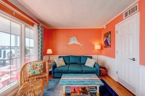 A cozy living room with a teal sofa, a wicker chair, and a striped coffee table. - Inn on Turville Cottage, Sleeps 4, Waterfront (Berlin)