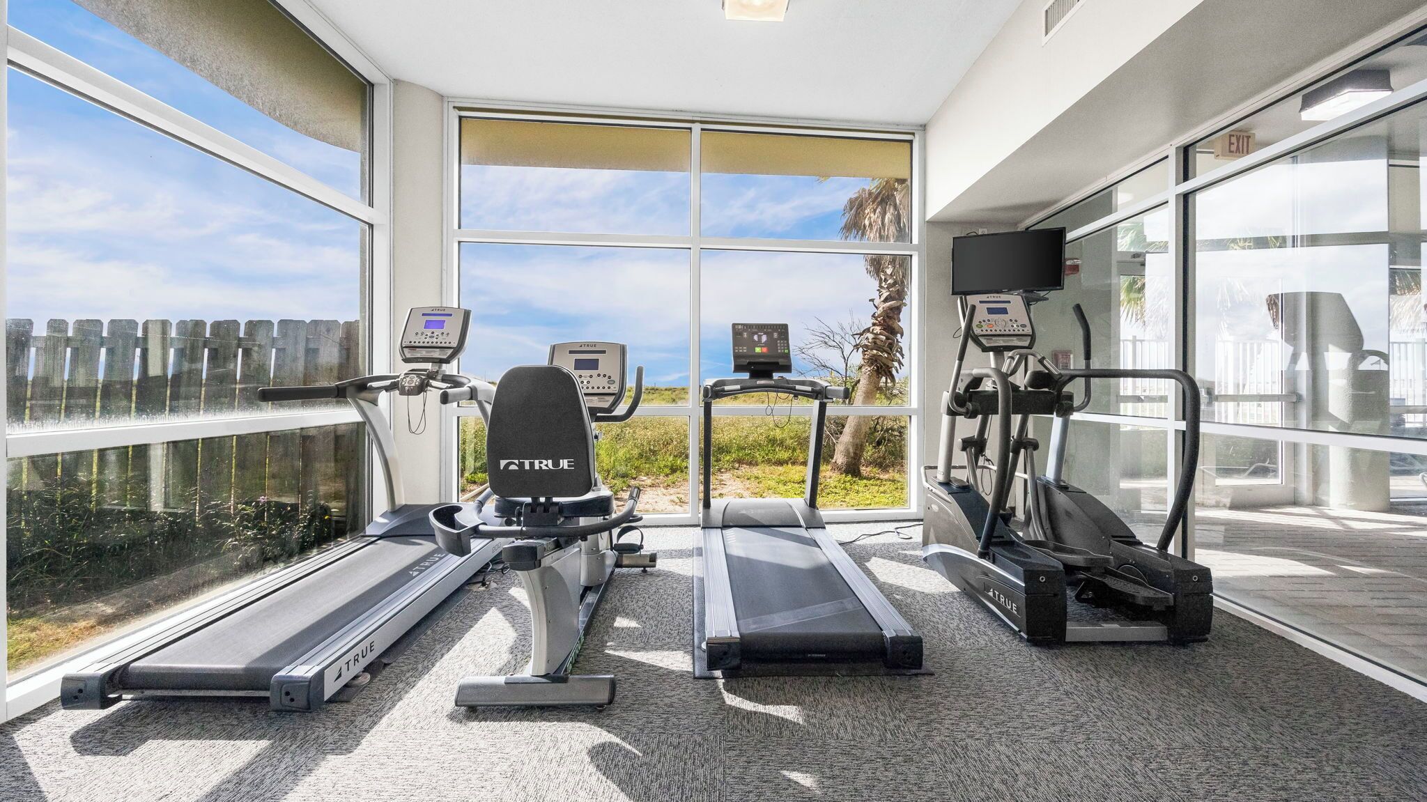 A fitness room with treadmills, a stationary bike, and a rowing machine, all equipped with digital displays.