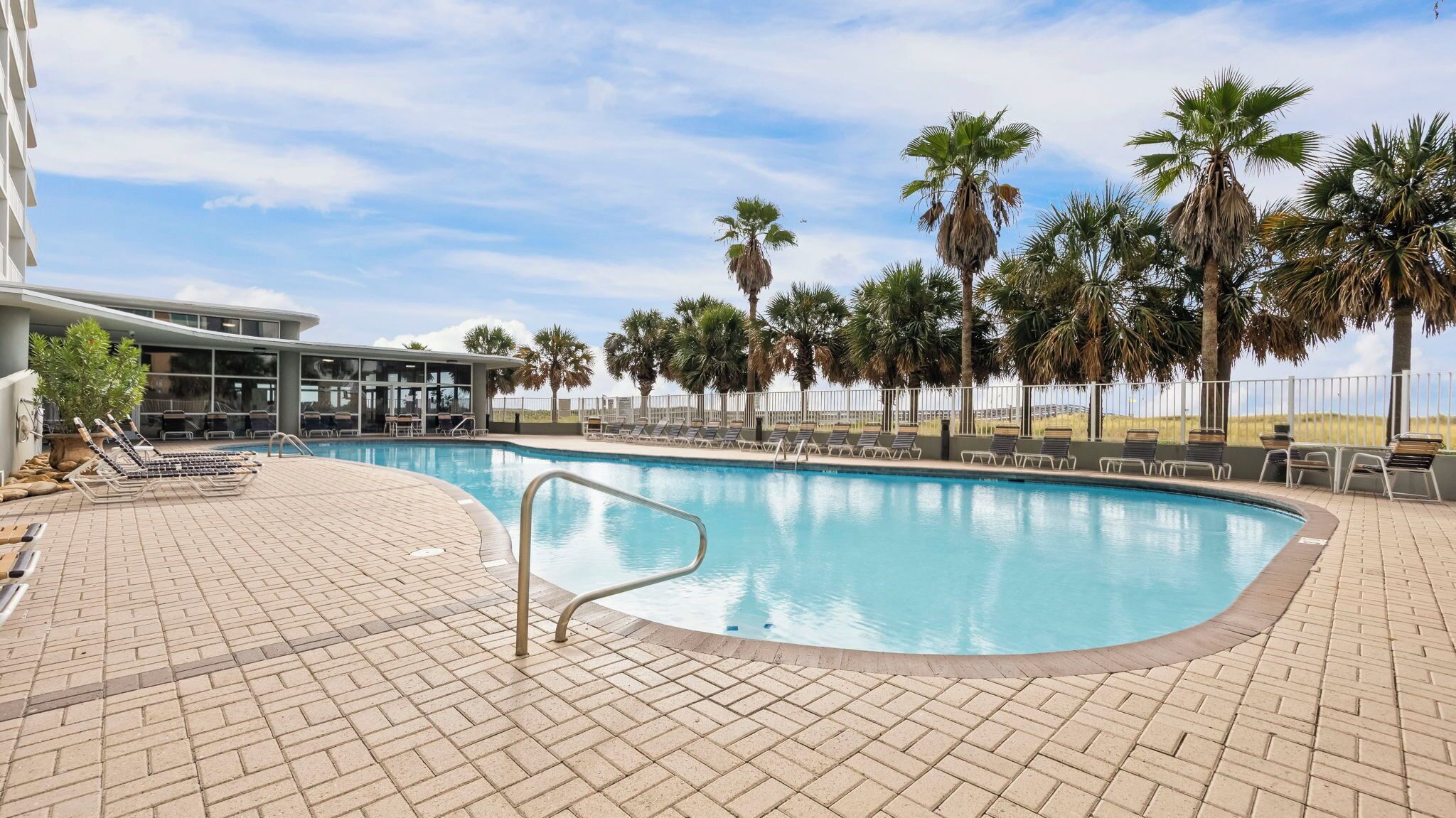 A swimming pool with lounge chairs and palm trees.