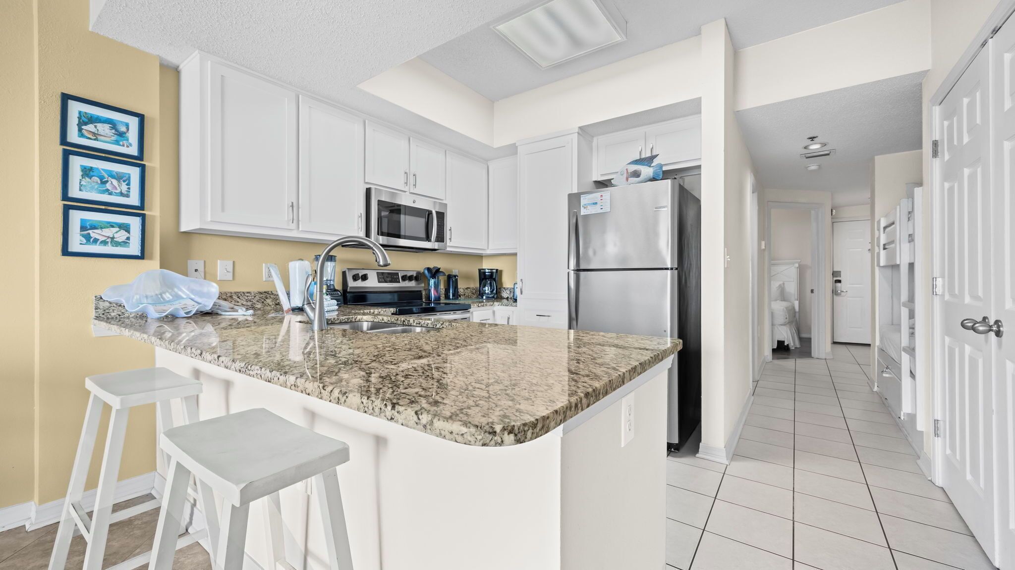 A modern kitchen with white cabinets, a granite countertop, and stainless steel appliances.