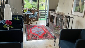 A living room with a fireplace, a large window, and a view of the outdoors. - Hotel Markgraf (Bad Bellingen)