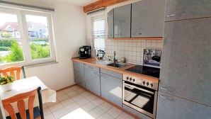 A kitchen with grey cabinets, a wooden countertop, a sink, and an oven.