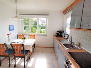 Una cucina con tavolo e sedie, una macchina per caffè e una finestra vista verde.