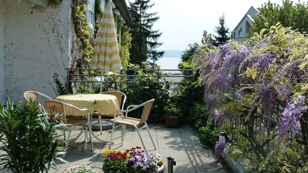 Un patio con mobiliario exterior, vistas al mar y una variedad de plantas.