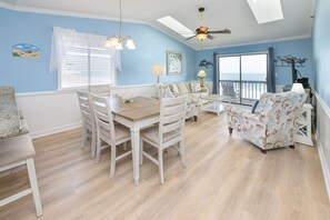 A dining area with a wooden table and chairs, a sofa, and a ceiling fan. - Oceanfront, Shared Pool - Surfwatch II 401 (Surfside Beach)