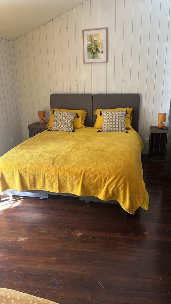 Un dormitorio con una cama grande, paredes de madera y un cuadro en la pared.