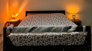 A bedroom with a skylight, a bed with floral bedding, two bedside lamps, and a nightstand. - Le Moulin De La Parenthèse (Sommières-du-Clain)