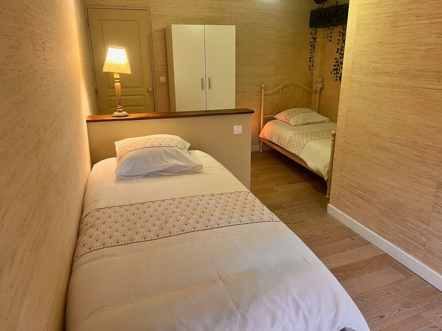 Ein kleines, gemütliches Schlafzimmer mit einem Einzelbett, einem Kleiderschrank und einem Nachttisch mit Lampe.