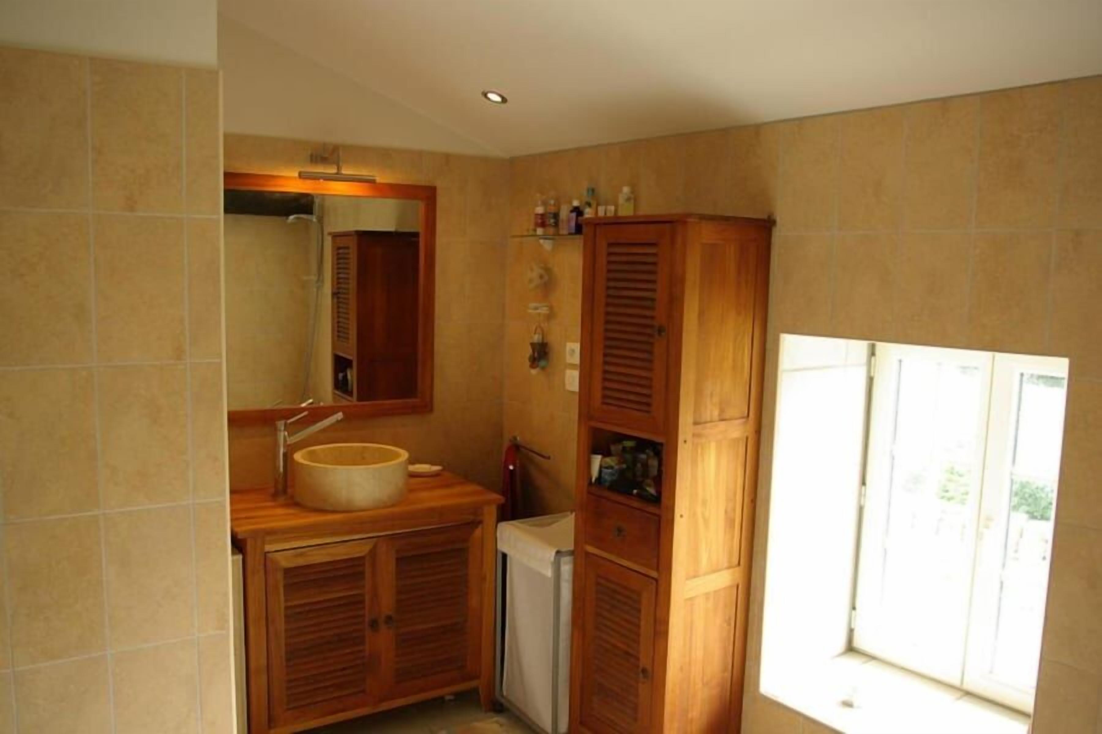 A bathroom with a wooden vanity, a sink, a mirror, and a window.