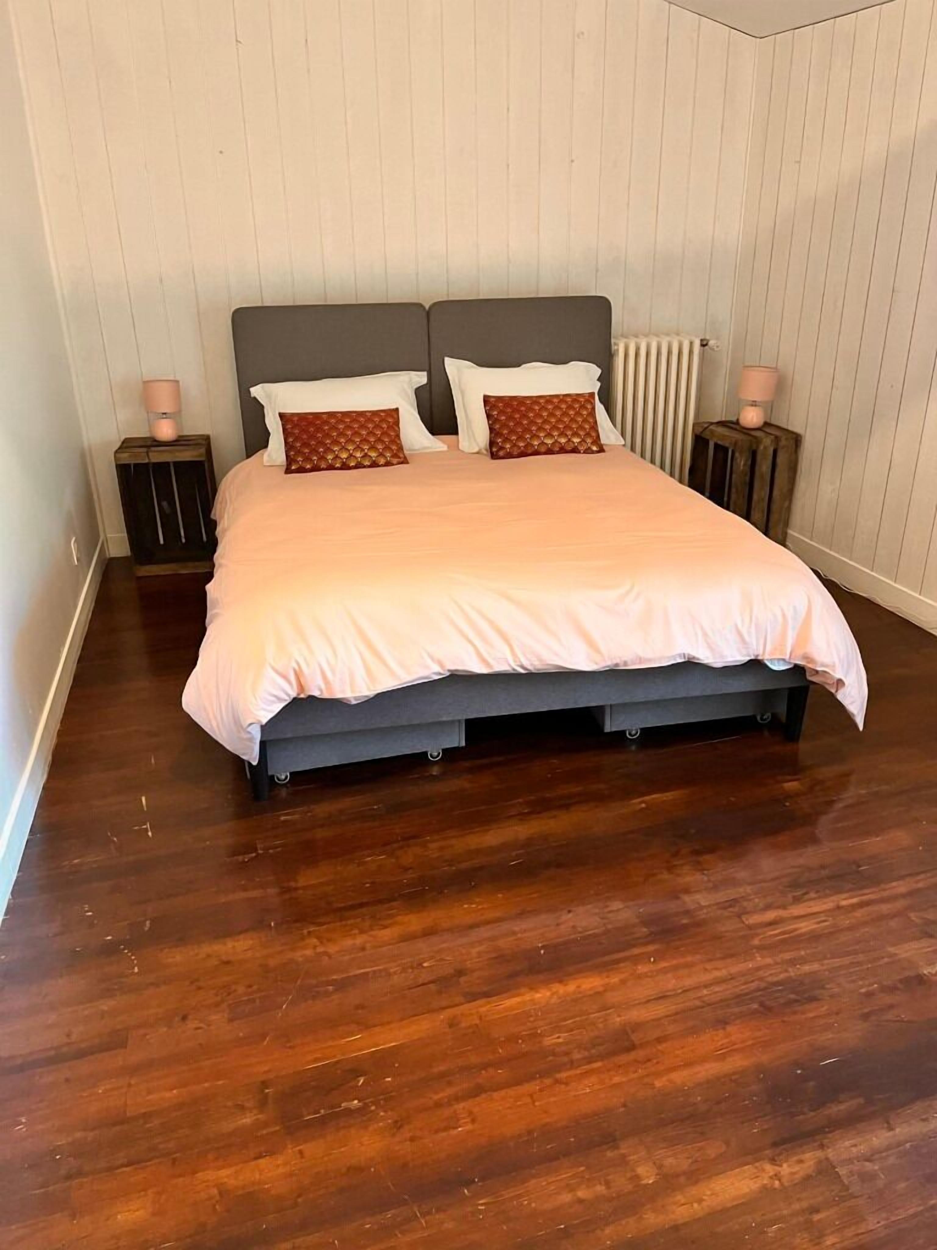 A bedroom with a bed, two nightstands, and a radiator.