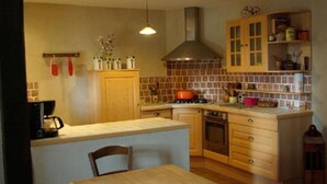A compact kitchen with a central island, wooden cabinets, and a tiled backsplash. - Le Moulin De La Parenthèse (Sommières-du-Clain)