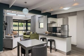 A modern kitchen with a dining area, large windows, and a view of the outdoors.