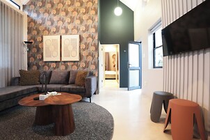 Una sala de estar moderna con un sofá seccional, una mesa redonda de centro y un televisor de pantalla plana montado en la pared.