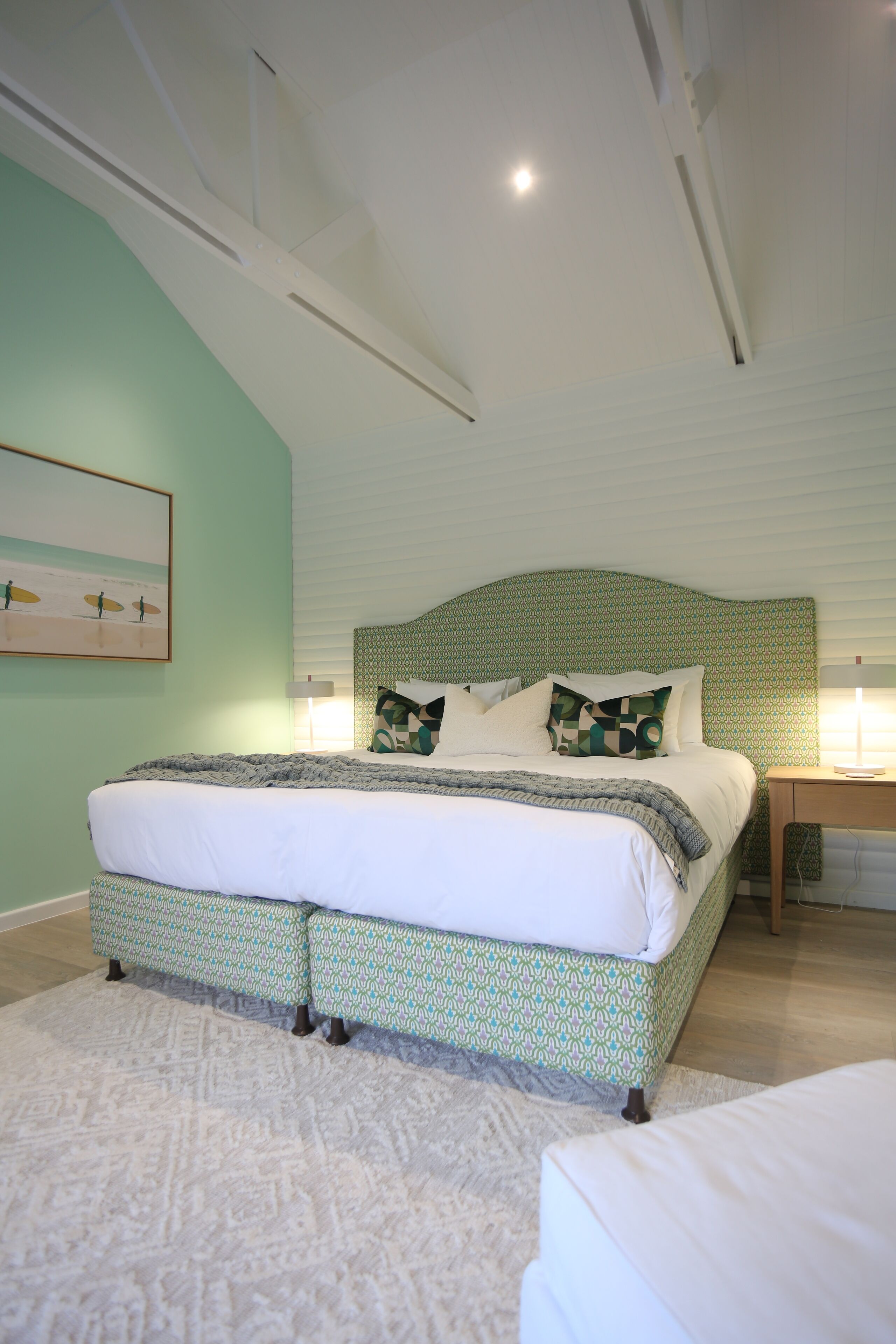 A bedroom with a large bed, a bedside table, and a wall-mounted lamp.