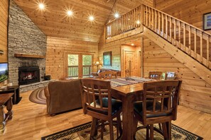 L’intérieur d’un chalet en bois comprend une cheminée, un coin repas et un escalier.
