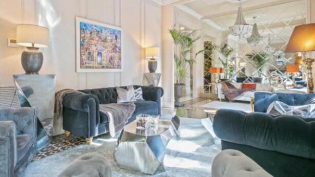 Un salon spacieux avec un grand canapé bleu, une table basse et un tableau accroché au mur.
