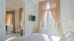 Une chambre d’hôtel avec un lit, des rideaux, une télévision et une fenêtre.