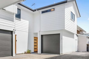 Ein modernes, zweistöckiges Haus mit Garage und einer kleinen Veranda.