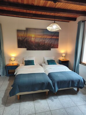 A double bed with matching pillows, two bedside tables with lamps, a large wall painting, and a wooden ceiling.